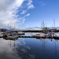 Port w Belfaście, gdzie jest? Widok na zacumowane jachty i łodzie pod błękitnym niebem z chmurami.