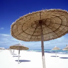 Słomiane parasole na pustej plaży w Tunezji. Nawet w lutym temperatura sprzyja relaksowi.