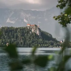 Jezioro Bled ze skalnym zamkiem, jedno z najpiękniejszych miejsc w Słowenii. Na pierwszym planie widać osobę na desce SUP.