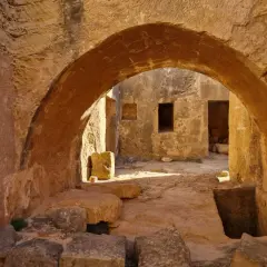 Kamienne łuki i korytarze w grobowcach królewskich Pafos, gdzie słońce rzuca długie cienie na starożytne mury.