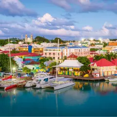 Kolorowe budynki portowe i jachty w **Antigua i Barbuda** o zachodzie słońca.