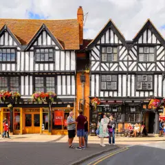 Urokliwe, zabytkowe budynki w Stratford-upon-Avon z charakterystyczną czarno-białą elewacją i kwiecistymi balkonami.