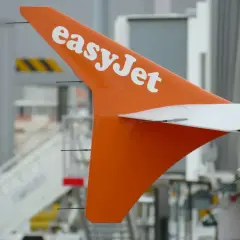 Pomarańczowy ogon samolotu easyJet z białym logo, gotowy do lotu. Idealny na bagaż podręczny.