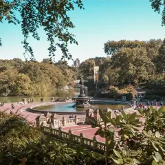 Central Park w Nowym Jorku: fontanna Bethesda z ludźmi spacerującymi wokół, w tle jezioro i drzewa.
