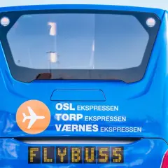 Niebieski Flybuss z napisem "OSL EKS<bos>. TORP EKS PRESEN", gotowy do podróży z lotniska Torp do centrum Oslo.