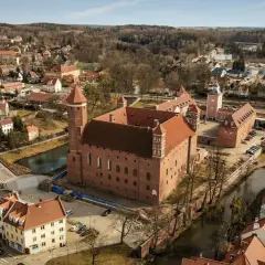 Lidzbark Warmiński atrakcje: imponujący zamek biskupów warmińskich otoczony fosą, malownicze miasteczko z czerwonymi dachami i amfiteatr.
