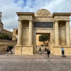 Łuk Triumfalny w Kordobie, wspaniały punkt na mapie "Kordoba co zobaczyć". Ludzie spacerują i jeżdżą na hulajnodze.