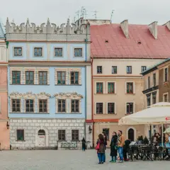 Kolorowe kamienice na rynku, idealne na tani wypad na weekend w Polsce. Ludzie spacerują i siedzą w ogródku kawiarnianym.