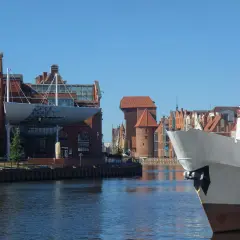 Co ciekawego w Gdańsku? Widok na Motławę z fragmentem statku i historyczną zabudową, w tym Żurawiem.