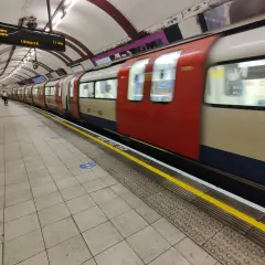 Metro londyn bilet 3 dniowy. Pociąg z czerwonymi i beżowymi elementami mija peron. Na tablicy informacja o odjeździe do Edgware.