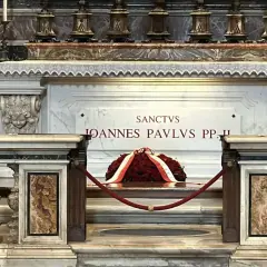 Grób Jana Pawła II w Watykanie. Marmurowa płyta z napisem "Sanctus Ioannes Paulus PP. II" i wieniec z czerwonych róż.
