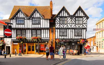 Urokliwe, zabytkowe budynki w Stratford-upon-Avon z charakterystyczną czarno-białą elewacją i kwiecistymi balkonami.