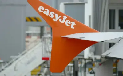 Pomarańczowy ogon samolotu easyJet z białym logo, gotowy do lotu. Idealny na bagaż podręczny.