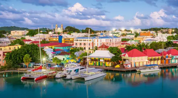 Kolorowe budynki portowe i jachty w **Antigua i Barbuda** o zachodzie słońca.