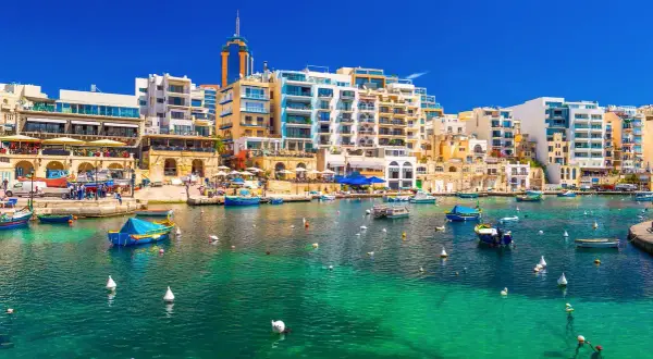 Malta, St Julian's: malowniczy port z turkusową wodą, łodziami i nowoczesnymi budynkami.