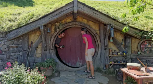 Para w Hobbiton w Nowej Zelandii pozuje przed okrągłymi drzwiami.