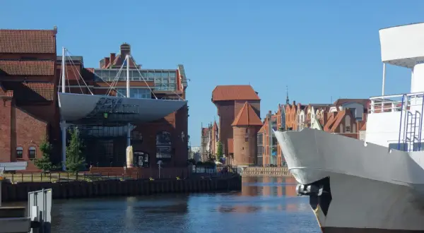 Co ciekawego w Gdańsku? Widok na Motławę z fragmentem statku i historyczną zabudową, w tym Żurawiem.