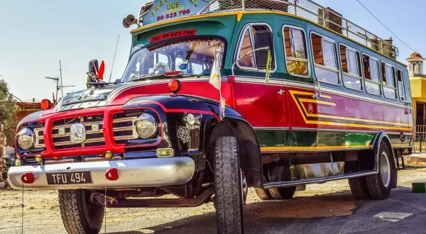 Tradycyjny autobus na Cyprze, kolorowy pojazd z napisem "Traditional Bus Cyprus" i numerem telefonu, stanowi unikatowy element komunikacji miejskiej.