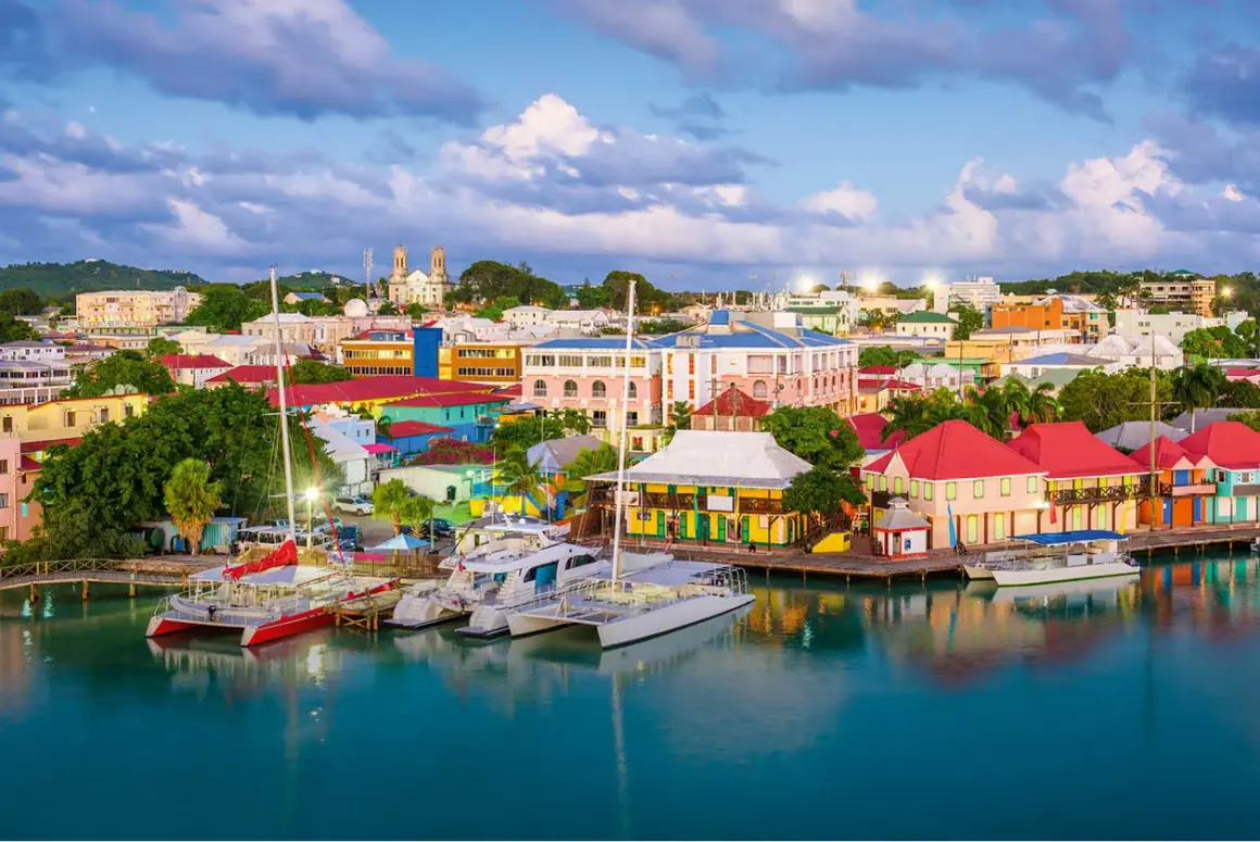 Kolorowe budynki portowe i jachty w **Antigua i Barbuda** o zachodzie słońca.