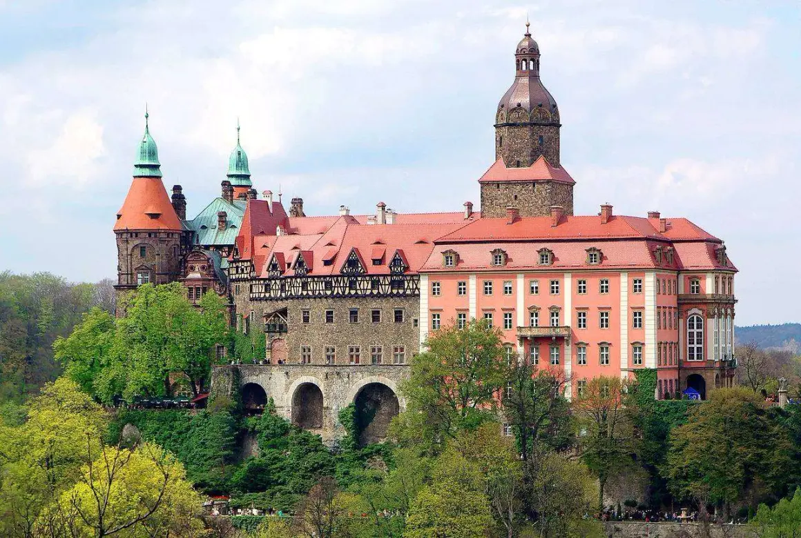 Imponujące zamki w okolicy Wrocławia, z wieżami i czerwonymi dachami, otoczone zielenią.