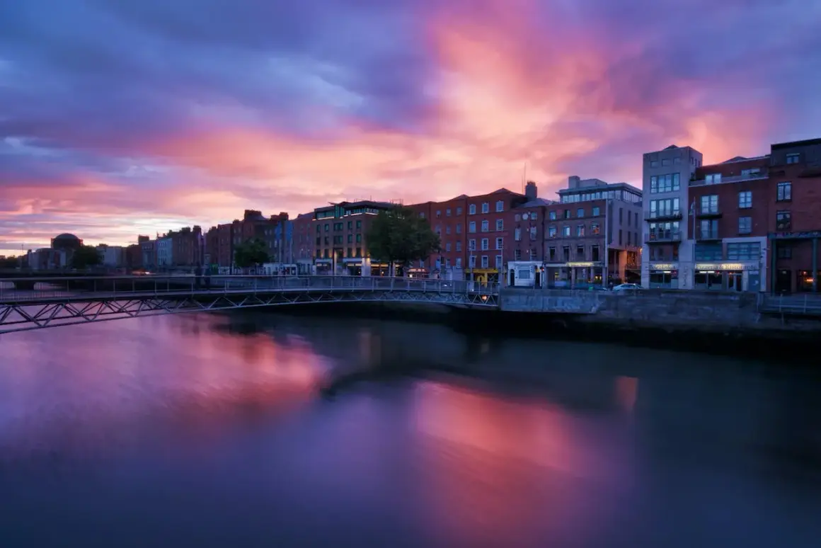 Zachód słońca nad rzeką Liffey w Dublinie. Warto zobaczyć te malownicze budynki i most w różowych barwach nieba.