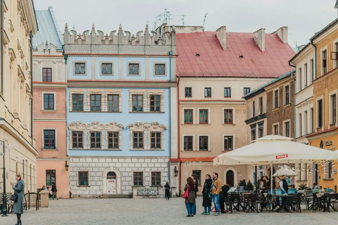 Kolorowe kamienice na rynku, idealne na tani wypad na weekend w Polsce. Ludzie spacerują i siedzą w ogródku kawiarnianym.