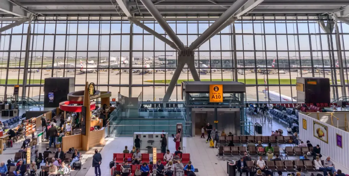 Wnętrze największego lotniska w Londynie, z widokiem na samoloty British Airways i pasażerów oczekujących na loty.