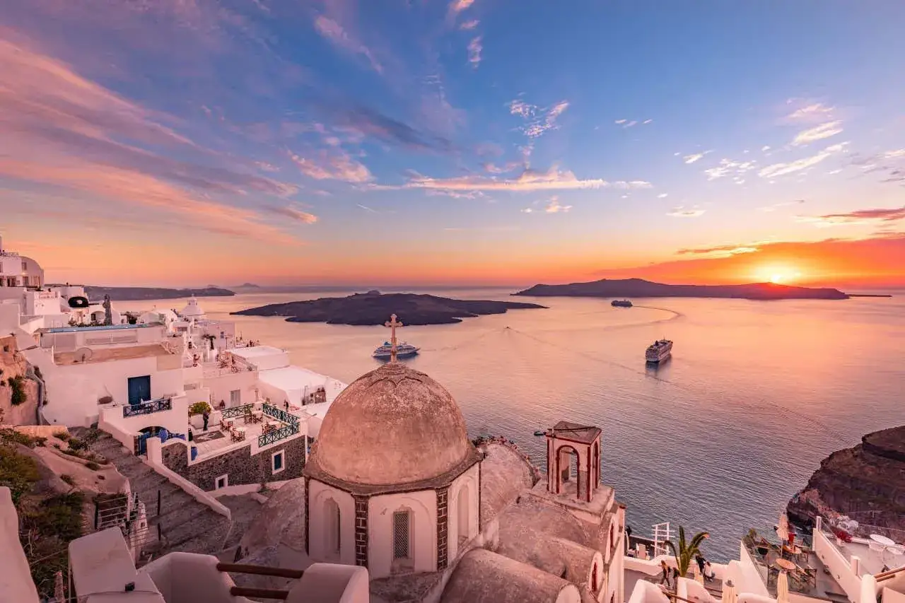 Santorini zachwyca o zachodzie słońca. Czy to najładniejsza wyspa grecka? Białe domy, błękitne morze i statki wycieczkowe tworzą magiczny widok.