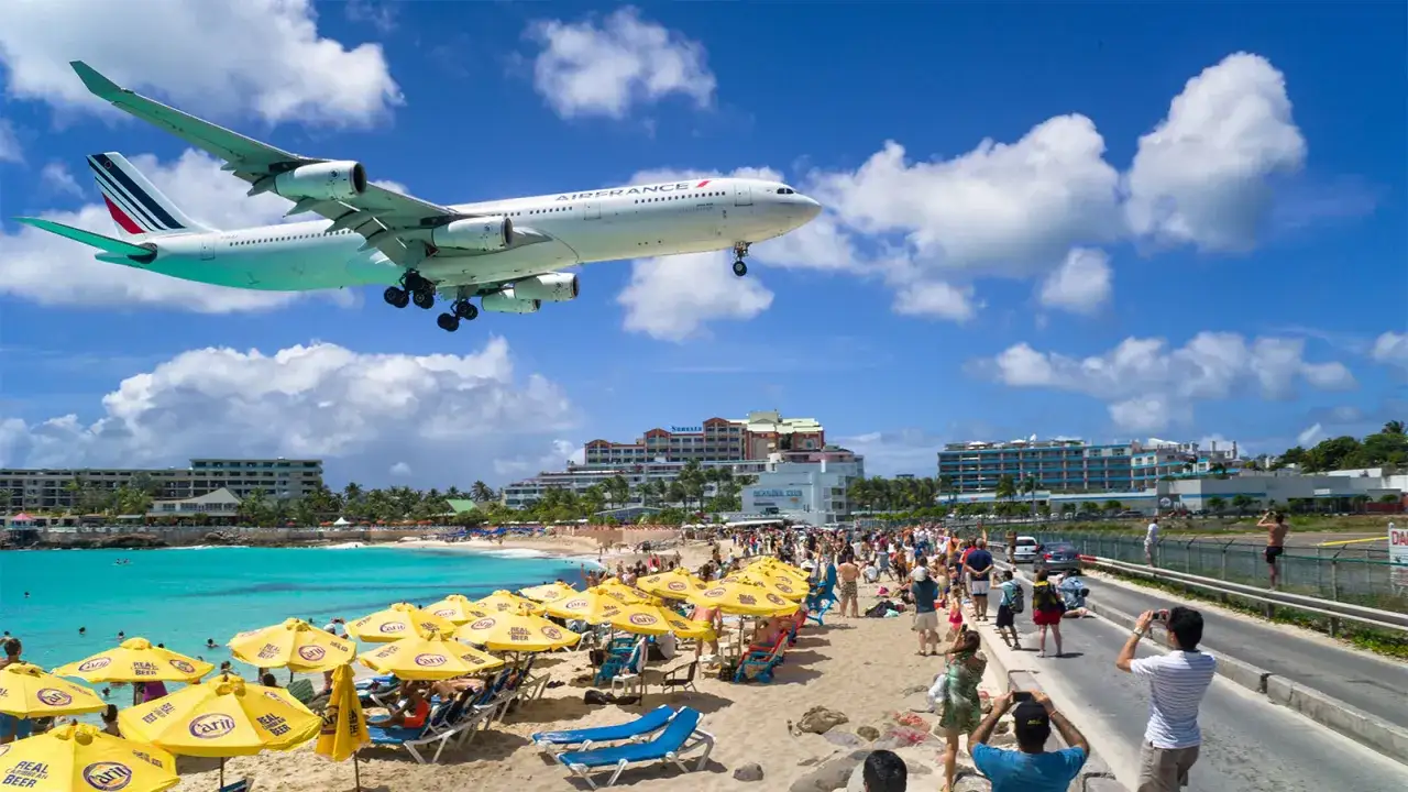 Samolot Air France przelatuje nisko nad plażą z turystami, przygotowując się do lądowania na najniebezpieczniejszym lotnisku na świecie.