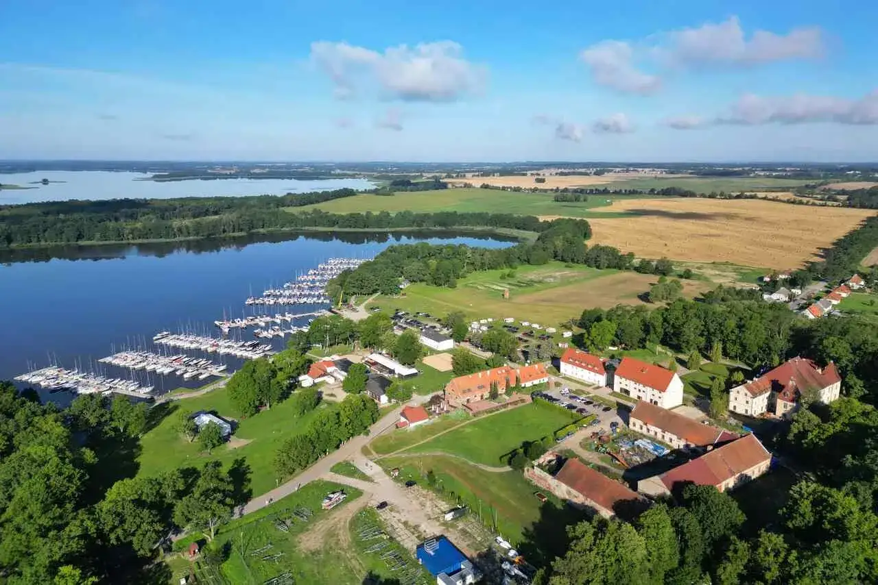 Malownicza zatoka z licznymi żaglówkami, idealna na długi weekend czerwiec. W tle pola i zabudowania.