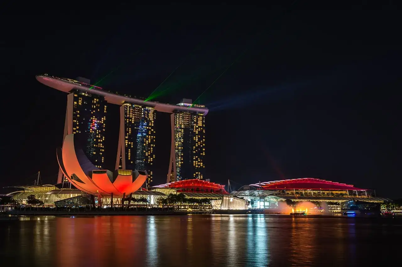 Nocny pokaz świateł na Marina Bay Sands w Singapurze. Woda odbija kolorowe iluminacje.