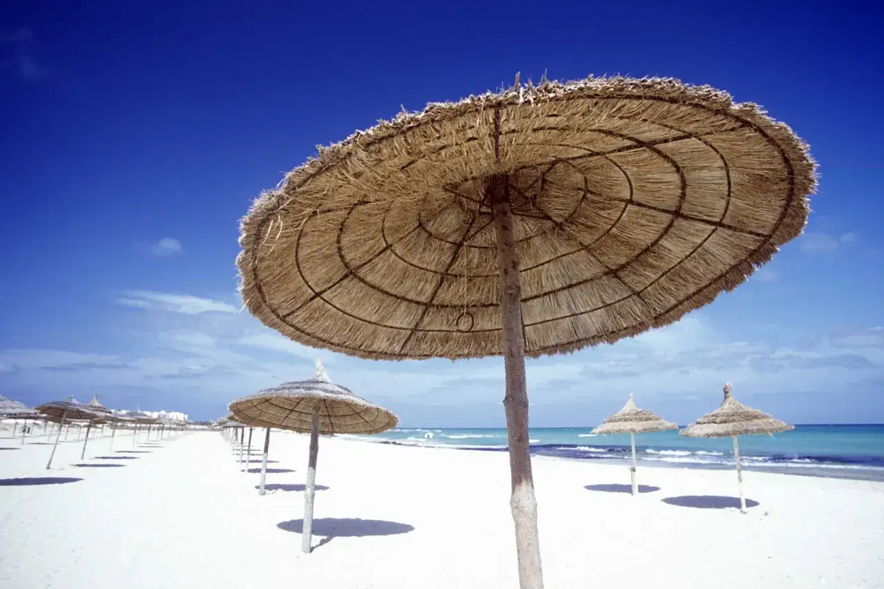 Słomiane parasole na pustej plaży. Piękna, słoneczna tunezja pogoda listopad, idealna na spokojny spacer.