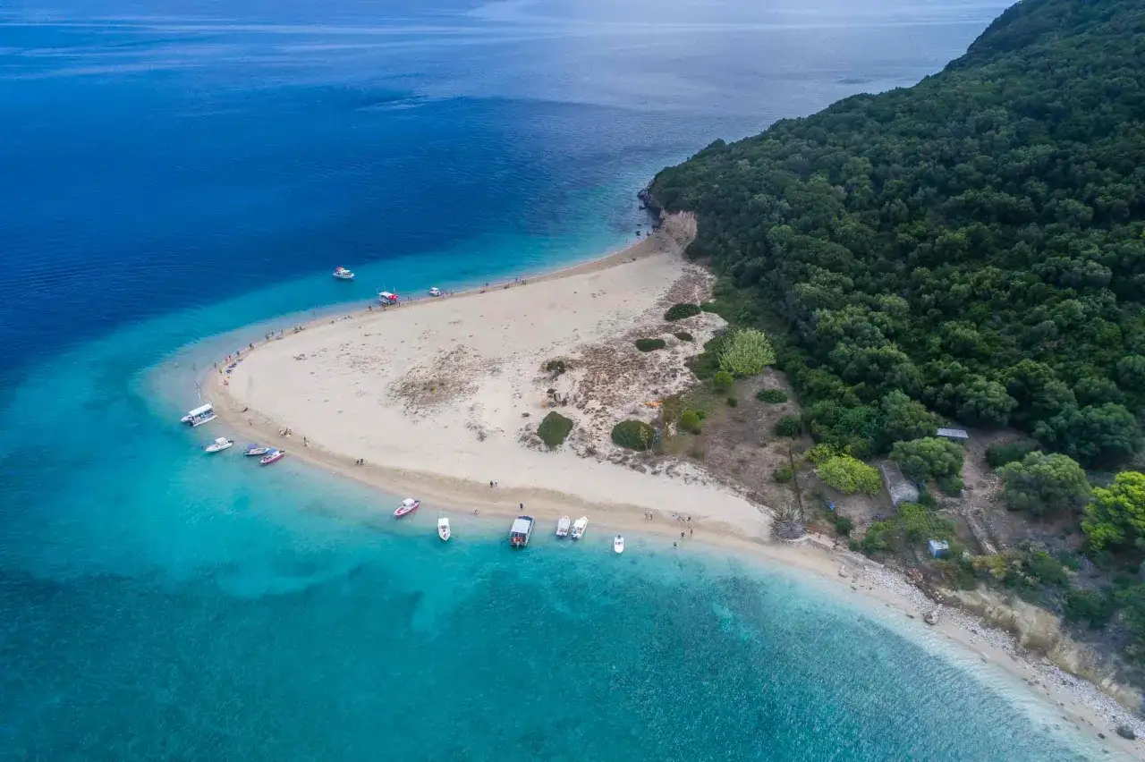 Idealna pogoda na Zakynthos w sierpniu: turkusowe morze, piaszczysta plaża i łodzie przy brzegu.