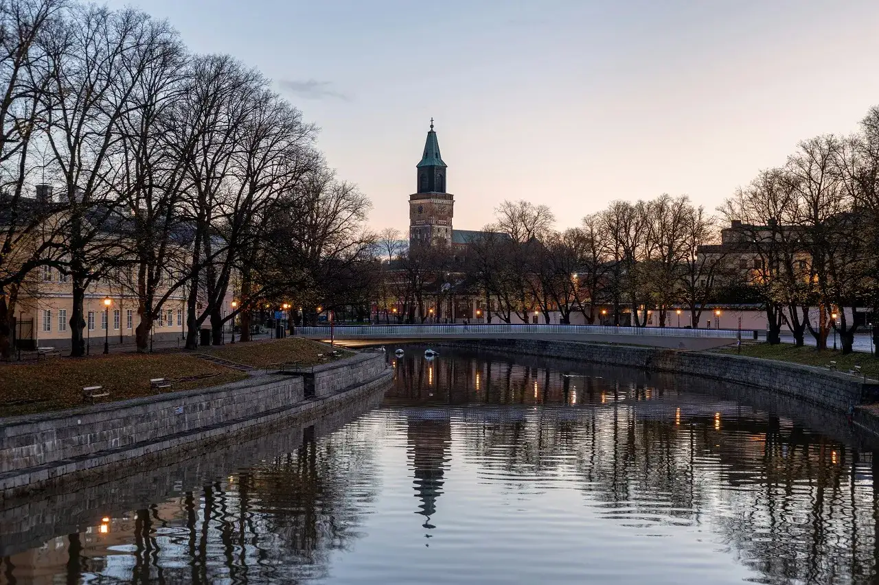 Wieczorna panorama Turku, najstarszego miasta Finlandii, z katedrą w tle i odbiciem drzew w rzece.